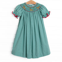  This dress features a green gingham print, puff sleeves, and a reindeer smockings. 