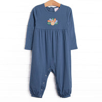  This romper features a blue knit material, snaps on the stride, and a turkey applique. 