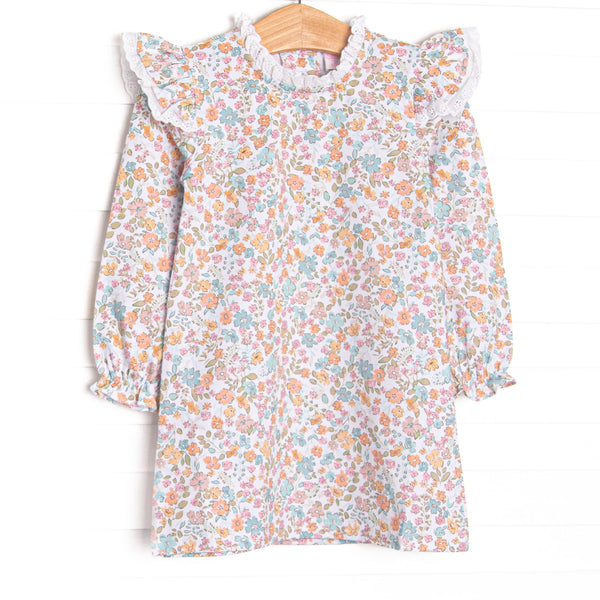  This dress features a blue floral print, eyelet lace trim, and long sleeves. 