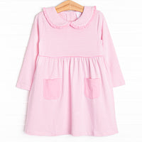 This dress features a pink stripes, front pockets, and a peter pan collar with ruffle trim. 