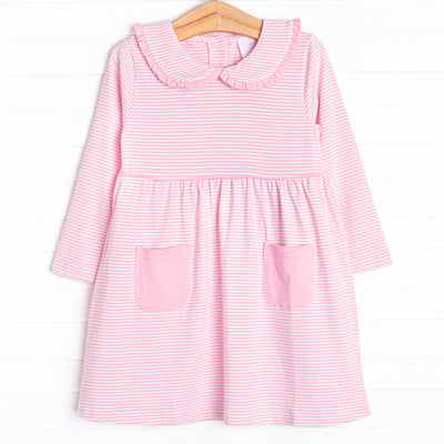  This dress features a pink stripes, front pockets, and a peter pan collar with ruffle trim. 