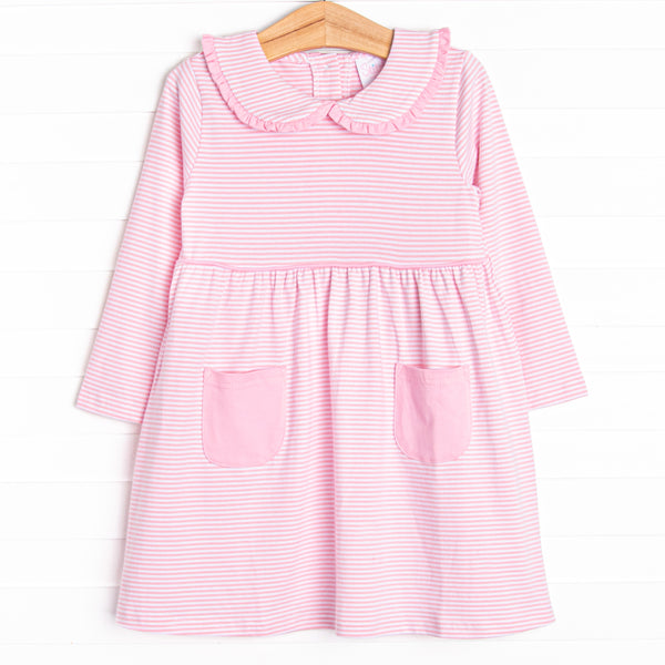  This dress features a pink stripes, front pockets, and a peter pan collar with ruffle trim. 