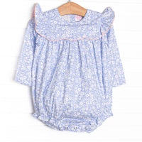  This bubble features a blue floral print, a ruffle bib with pink trim, and snaps on the stride. 