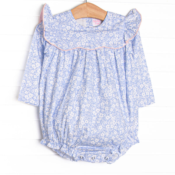  This bubble features a blue floral print, a ruffle bib with pink trim, and snaps on the stride. 