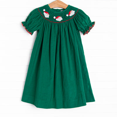  This dress features a green corduroy material, puff sleeves with red picot trim, and Santa Claus smockings