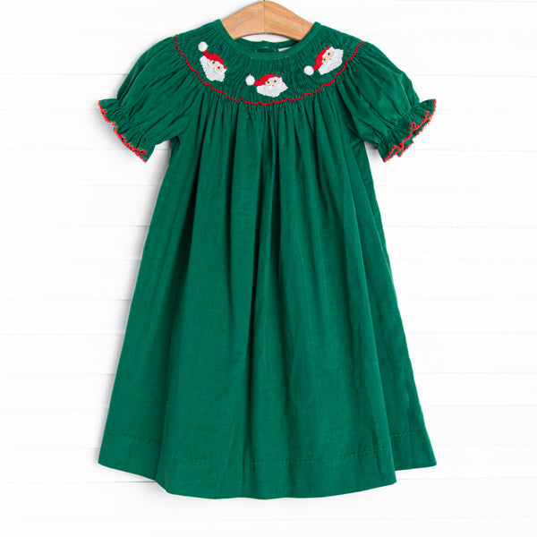  This dress features a green corduroy material, puff sleeves with red picot trim, and Santa Claus smockings