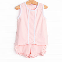  This set features a pink knit material, white trim, and ruffle shorts to match. 