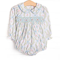 his bubble features a blue floral print, a Peter Pan collar, and a dainty rose smocking. 