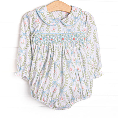 his bubble features a blue floral print, a Peter Pan collar, and a dainty rose smocking. 