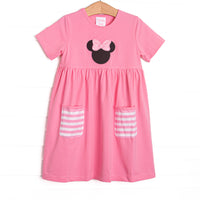  A bright pop of pink, coupled with pink and white striped pockets has us ready for a magical adventure. A mouse ears applique with a whimsical polka dot bow adorns the front of this dress. 