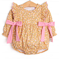 This bubble features a yellow floral print, ruffle trim, and pink bows on the sides.