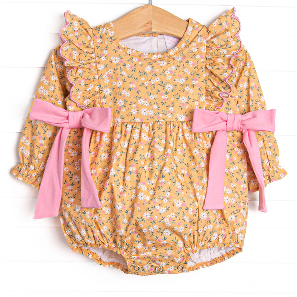 This bubble features a yellow floral print, ruffle trim, and pink bows on the sides.
