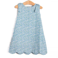  This dress features a blue floral print, shoulder bows, and scalloped trim. 
