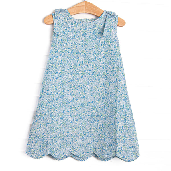  This dress features a blue floral print, shoulder bows, and scalloped trim. 