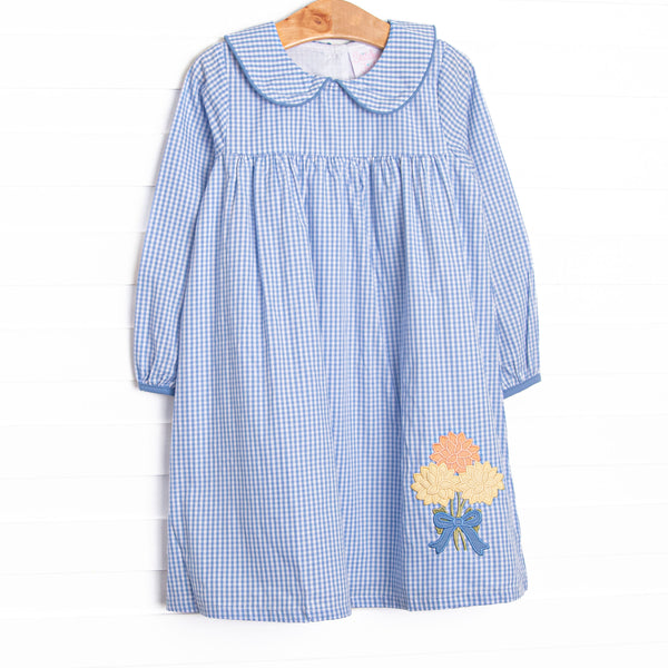  This dress features a blue gingham fabric, a blue Peter Pan collar, and a mum applique. 