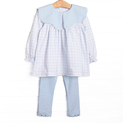 This set features a blue gingham print, a blue scalloped bib collar, and long sleeves. Coordinating blue leggings to match.