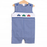 This jon jon features a royal blue gingham. snaps on the stride, and trio of cars smockings.