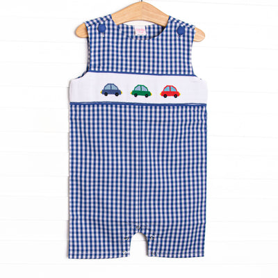 This jon jon features a royal blue gingham. snaps on the stride, and trio of cars smockings.