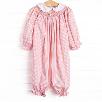 This romper features a pink gingham print, a peter pan collar with ric rac trim, and a rocking horse smocking.