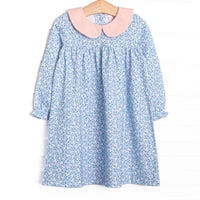 This dress features a blue floral print, a pink ruffle neck, and a front pocket.