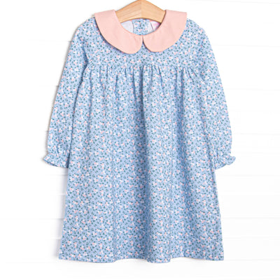 This dress features a blue floral print, a pink ruffle neck, and a front pocket.