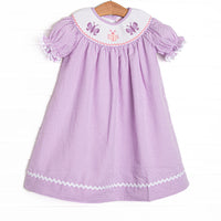 This dress features a purple seersucker print, white ric rac trim, and butterfly smockings