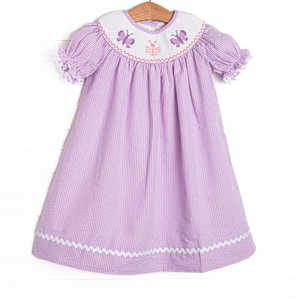 This dress features a purple seersucker print, white ric rac trim, and butterfly smockings