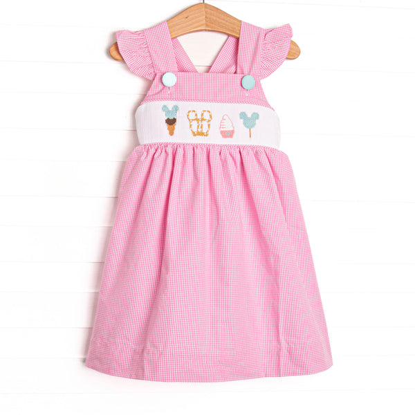 This dress features a pink gingham print, flutter sleeves, and a magical treat smocking.