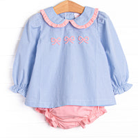 This set features a blue gingham print, a peter pan collar with pink ruffle trim, and a trio of bow embroideries. Coordinating pink diaper cover to match