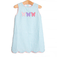 This dress features an mint green gingham print, pink trim, and a trio of butterfly applique.