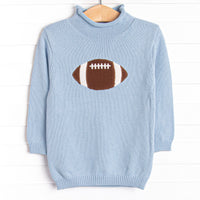 This sweater features a blue material, a rolled neck, and a football icon.