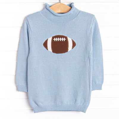 This sweater features a blue material, a rolled neck, and a football icon.