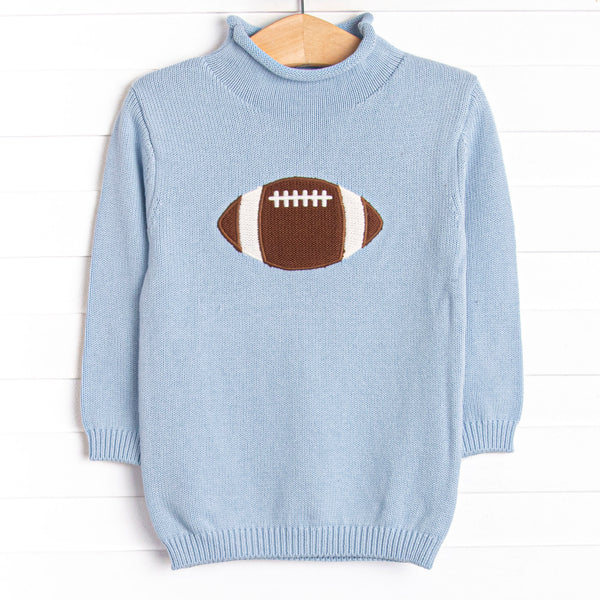 This sweater features a blue material, a rolled neck, and a football icon.