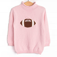 This sweater features a pink material, a rolled neck, and a football icon.