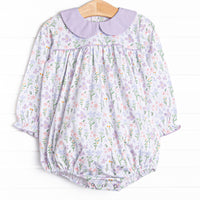 This bubble&nbsp; features a purple floral print, a purple peter pan collar and snaps on the stride to make changing a breeze.