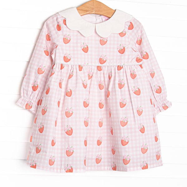 This dress features pink gingham and strawberry printed fabric, a white scalloped collar, and long sleeves.