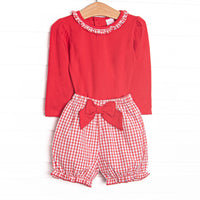 his set features a red top, a windowpane ruffle collar, and windowpane bloomer shorts with a red bow.