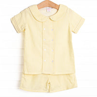 This set features a yellow seersucker print, a peter pan collar, and front covered buttons. Coordinating yellow seersucker shorts to match.