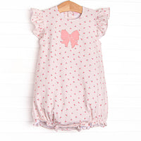  This bubble features a dainty pink floral print, flutter sleeves, and a pink bow applique. 
