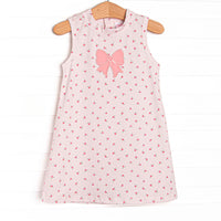 This dress features a dainty pink floral print, button closure on the back, and a pink bow applique.
