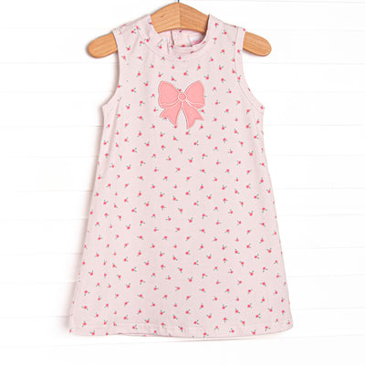 This dress features a dainty pink floral print, button closure on the back, and a pink bow applique.