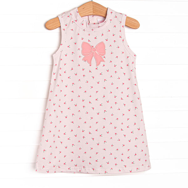 This dress features a dainty pink floral print, button closure on the back, and a pink bow applique.