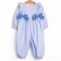  This romper features a blue gingham print, blue bows and ruffle trim. 