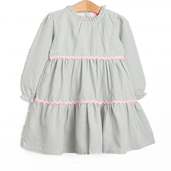  This dress features a sage gingham print, pink ric rac trim, and button closure on the back. 