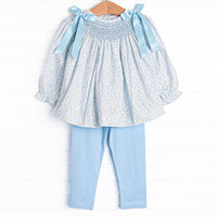 A long sleeve top with a blue smocking and blue bow details on the shoulders. Coordinating blue leggings to match.