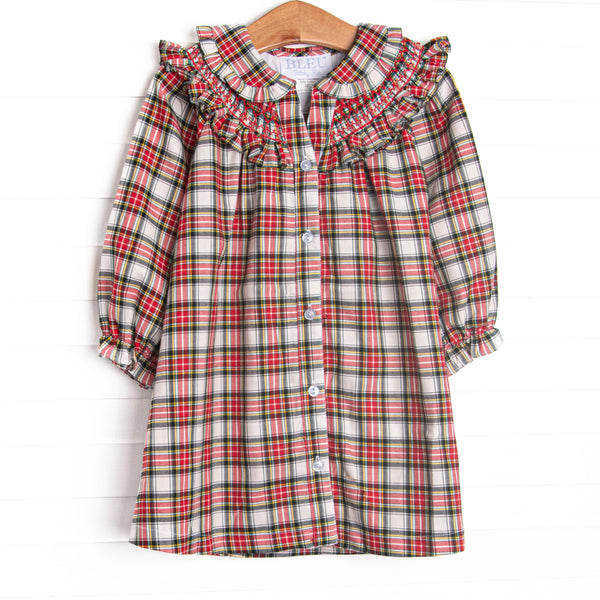 This dress features a red tartan fabric, dainty smocking, and beautiful ruffle trimmed Peter Pan collar.