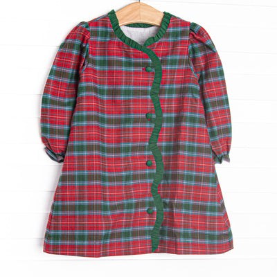  This dress features a red and green plaid fabric, ruffle trim, and front buttons. 