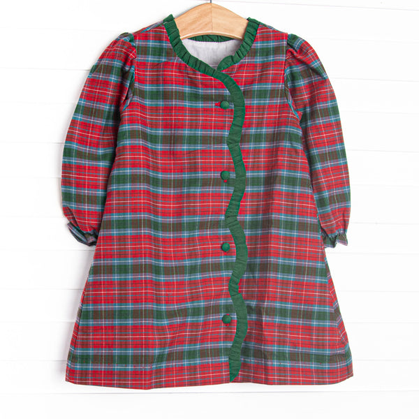  This dress features a red and green plaid fabric, ruffle trim, and front buttons. 