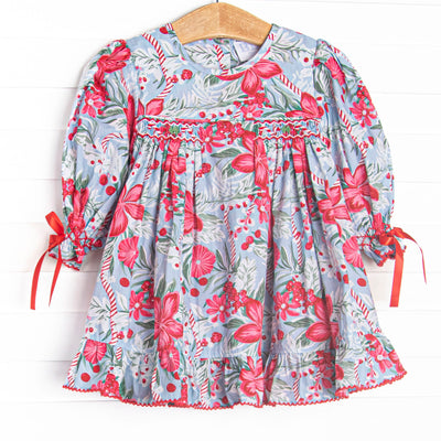 This dress features a blue floral fabric, dainty smocking, and ribbon sleeve ties.