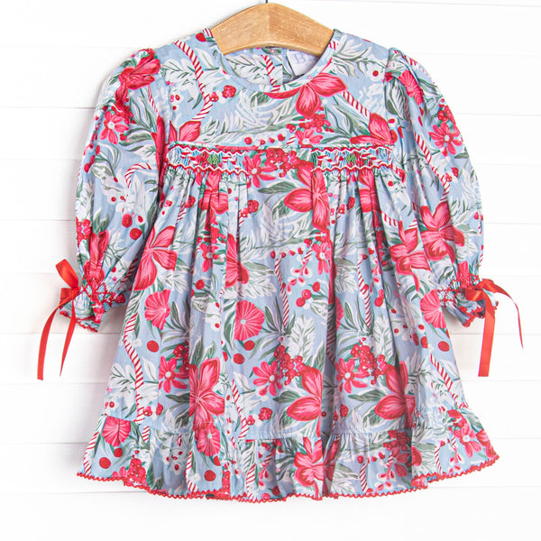 This dress features a blue floral fabric, dainty smocking, and ribbon sleeve ties.